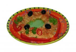 Ein Teller mit Humus, garniert mit Paprika, Oliven und Schnittlauch