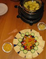 Ein angerichtetes Raclette mit Kartoffeln, Käse und Beilagen